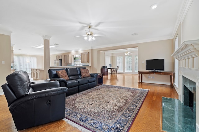 living room featuring a wealth of natural light, a premium fireplace, a ceiling fan, and ornamental molding