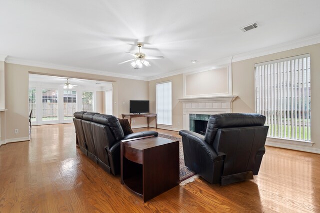 living room featuring ceiling fan, ornamental molding, visible vents, a high end fireplace, and wood finished floors
