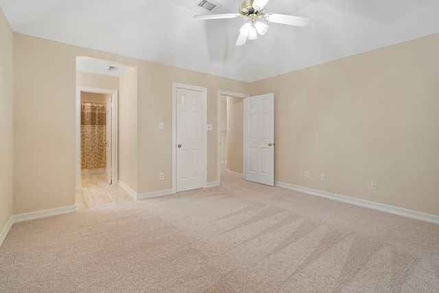 unfurnished bedroom with light colored carpet, ensuite bathroom, a ceiling fan, and baseboards