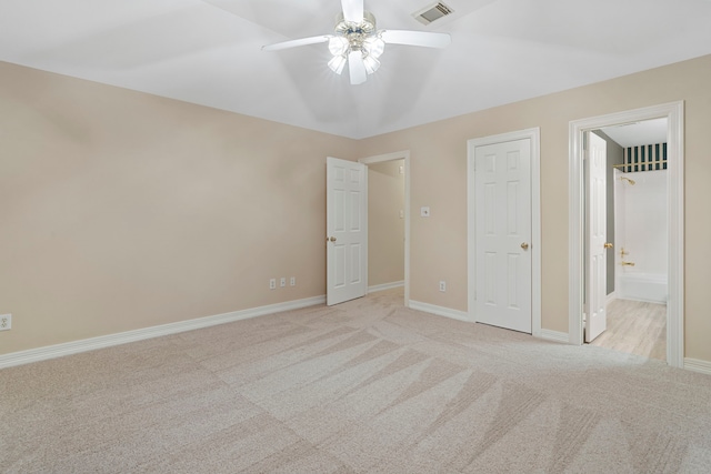 unfurnished bedroom with baseboards, visible vents, ensuite bathroom, and light colored carpet