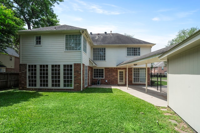 back of house featuring a patio, a lawn, brick siding, and fence