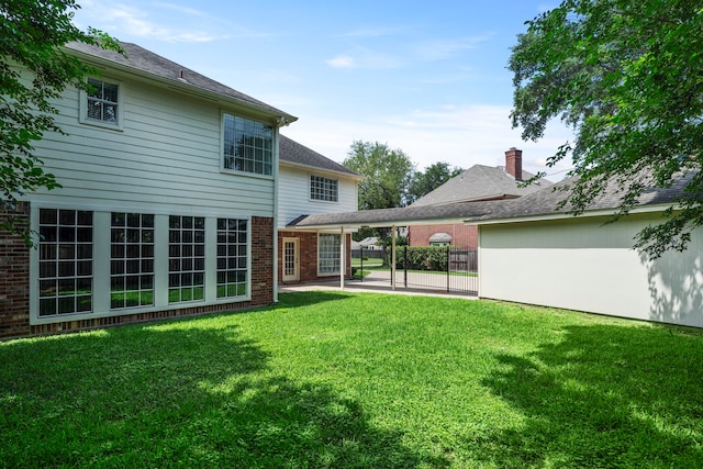 rear view of house featuring a lawn, fence, a patio, and brick siding