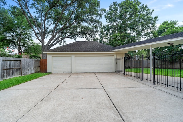 garage featuring fence and concrete driveway
