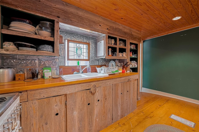 kitchen with a sink, open shelves, light wood finished floors, and butcher block countertops