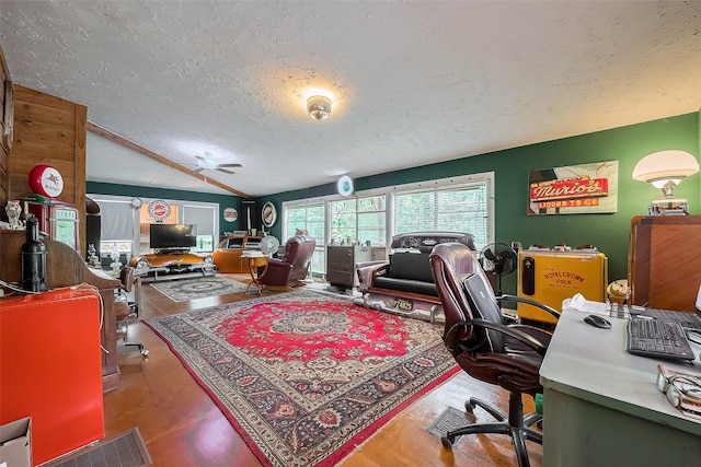 home office with a ceiling fan, a textured ceiling, wood finished floors, and vaulted ceiling