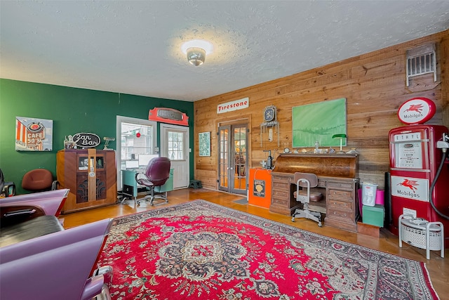 office with wooden walls, french doors, a textured ceiling, and wood finished floors