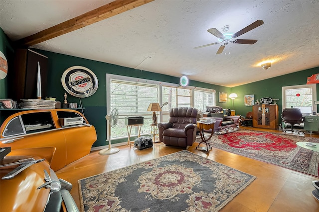living room with lofted ceiling with beams, a textured ceiling, ceiling fan, and wood finished floors