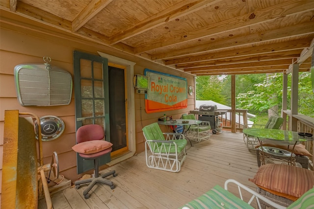 wooden terrace featuring area for grilling and outdoor dining area