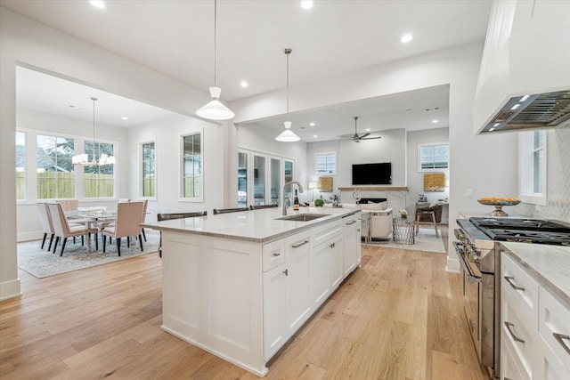 714 E 21st St, Houston, TX 77008 - kitchen with light stone counters, custom range hood, high end stove, a sink, and open floor plan