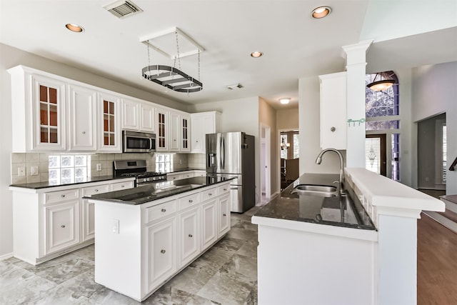 120 Calypso Ln, League City, TX 77573 - kitchen featuring stainless steel appliances, a sink, backsplash, white cabinetry, and a peninsula