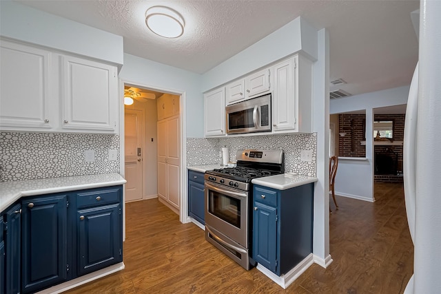 2307 Country Place Dr, Richmond, TX 77406 - kitchen with white cabinets, stainless steel appliances, wood finished floors, and blue cabinetry
