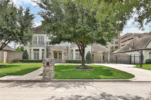 view of front of house with a gate, a front lawn, french doors, and stone siding