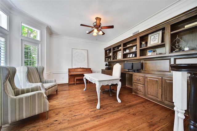 office space with ceiling fan, visible vents, wood finished floors, built in study area, and ornamental molding