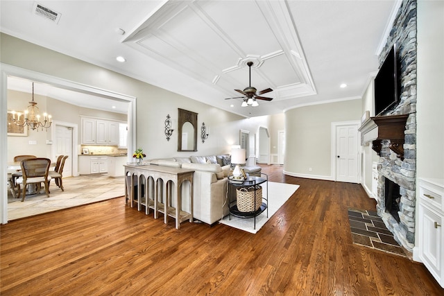 living room featuring crown molding, a fireplace, ceiling fan with notable chandelier, recessed lighting, and wood finished floors