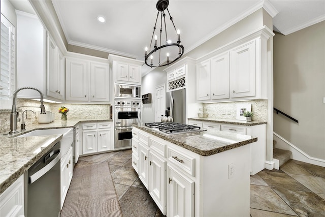 kitchen featuring a notable chandelier, appliances with stainless steel finishes, a sink, tasteful backsplash, and a kitchen island
