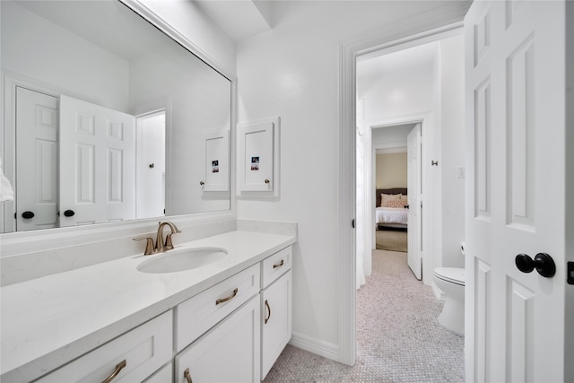 ensuite bathroom with vanity, connected bathroom, baseboards, and toilet