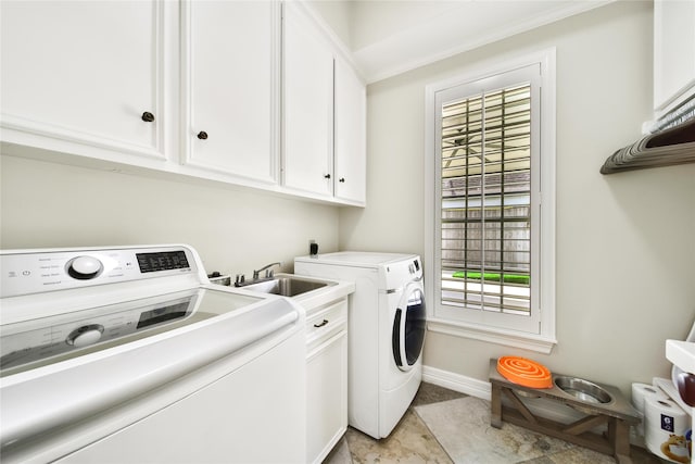 washroom featuring crown molding, cabinet space, a sink, baseboards, and washer and clothes dryer