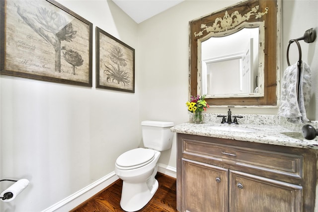 bathroom featuring baseboards, vanity, toilet, and wood finished floors
