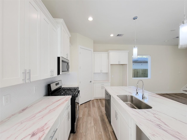 5931 Beall St Unit D, Houston, TX 77091 - kitchen featuring light stone countertops, a sink, light wood-type flooring, visible vents, and appliances with stainless steel finishes