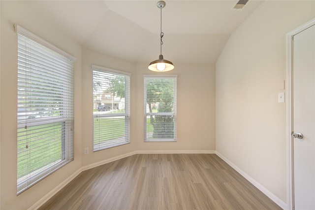 unfurnished dining area with light wood finished floors, visible vents, baseboards, and vaulted ceiling
