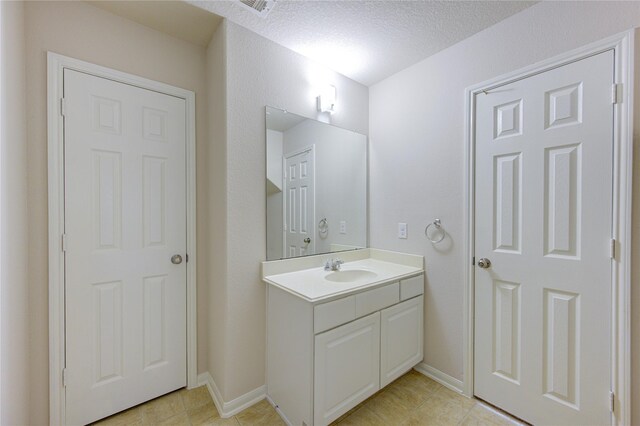 bathroom featuring tile patterned floors, a textured ceiling, baseboards, and vanity