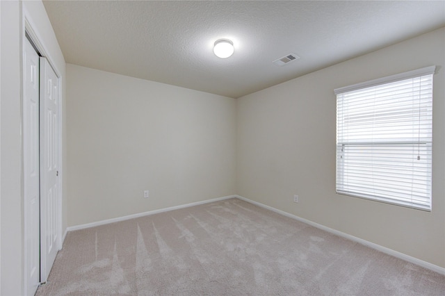unfurnished bedroom with baseboards, light carpet, and visible vents