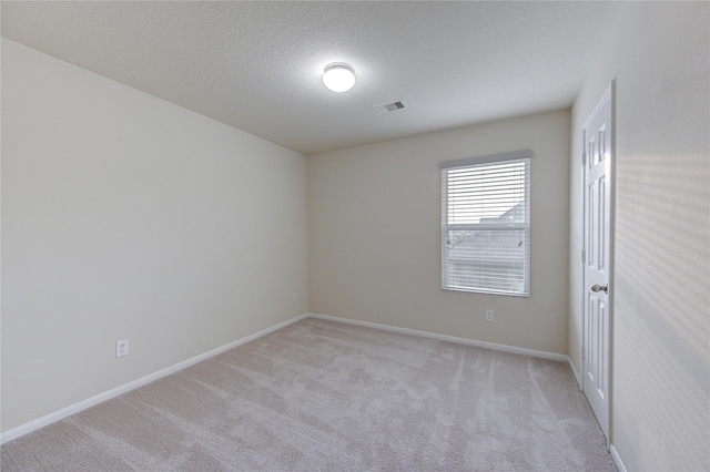 spare room with visible vents, baseboards, and light carpet