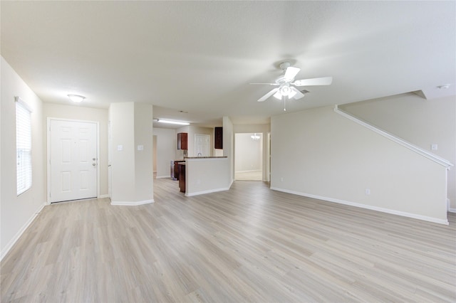 unfurnished living room with light wood-style flooring, baseboards, and ceiling fan