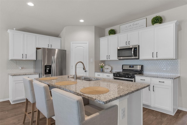 18320 Klamath Falls Ln, New Caney, TX 77357 - kitchen with stainless steel appliances, dark wood finished floors, backsplash, a kitchen island with sink, and a kitchen breakfast bar