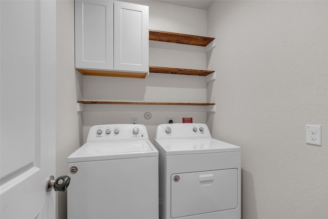 washroom featuring cabinet space and washer and clothes dryer