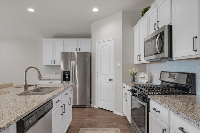 kitchen with a sink, appliances with stainless steel finishes, white cabinetry, and dark wood-type flooring