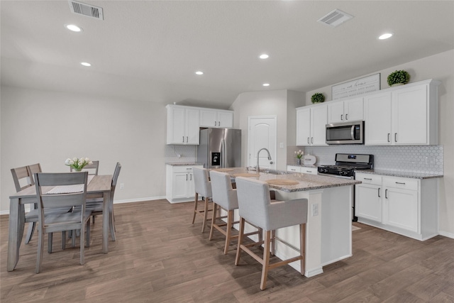 kitchen with stainless steel appliances, visible vents, decorative backsplash, and a sink