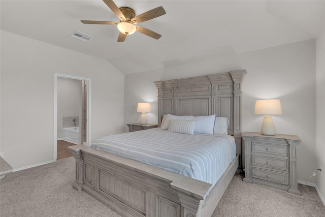 bedroom featuring visible vents, vaulted ceiling, baseboards, light carpet, and ensuite bath