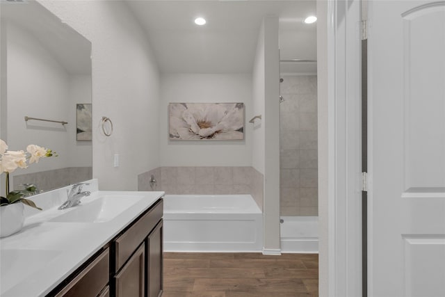 full bathroom with a sink, a tile shower, wood finished floors, and a garden tub