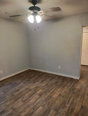 414 Future St, Palestine, TX 75801 - unfurnished room with ceiling fan, dark wood finished floors, and baseboards