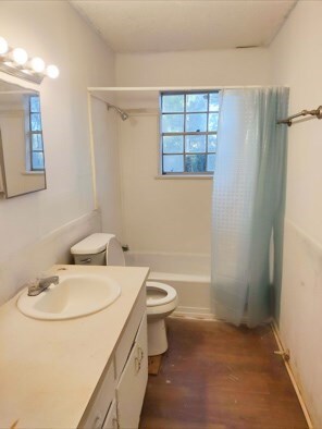 414 Future St, Palestine, TX 75801 - bathroom featuring vanity, toilet, wood finished floors, and shower / tub combo with curtain