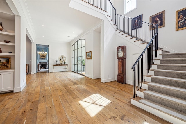 entryway with baseboards, stairway, light wood-type flooring, and crown molding