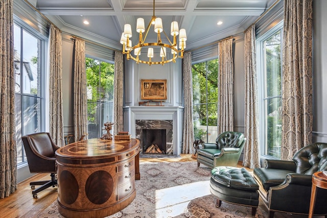living area with crown molding, plenty of natural light, coffered ceiling, wood finished floors, and a notable chandelier