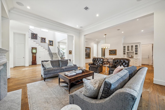 living area with crown molding, stairway, light wood-type flooring, recessed lighting, and a fireplace