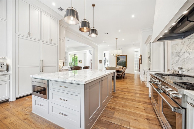 kitchen with tasteful backsplash, appliances with stainless steel finishes, wall chimney range hood, visible vents, and crown molding