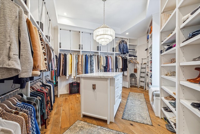 spacious closet with a tray ceiling and light wood-style floors
