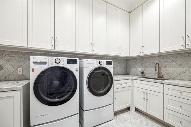 laundry area featuring washer and clothes dryer, cabinet space, marble finish floor, and a sink
