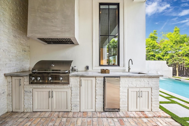 view of patio featuring an outdoor pool, grilling area, a sink, and an outdoor kitchen