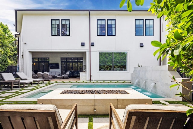rear view of property featuring a fire pit, fence, and stucco siding