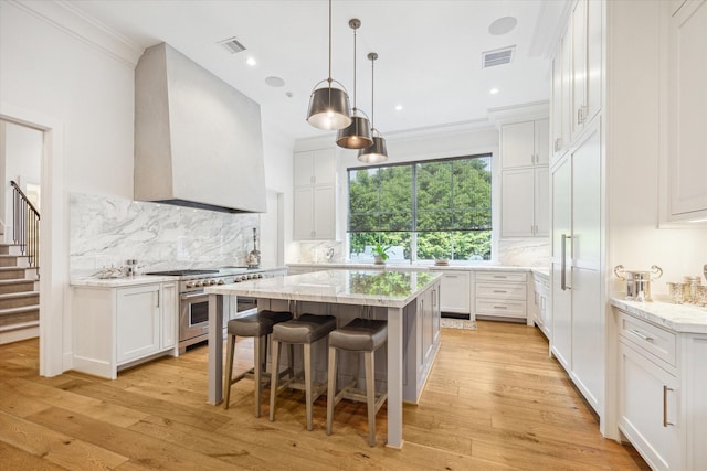 kitchen with range with two ovens, visible vents, light stone countertops, and white cabinetry