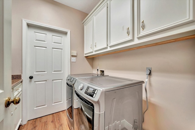 clothes washing area featuring light wood-type flooring, cabinet space, and washing machine and clothes dryer