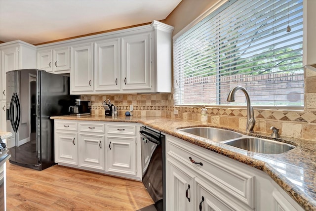 kitchen with a sink, white cabinetry, black appliances, and decorative backsplash