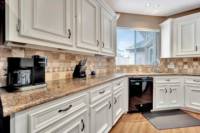 kitchen featuring a sink, white cabinetry, black dishwasher, and decorative backsplash