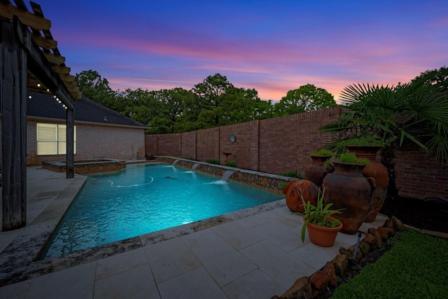 pool at dusk with a patio, a pool with connected hot tub, and a fenced backyard