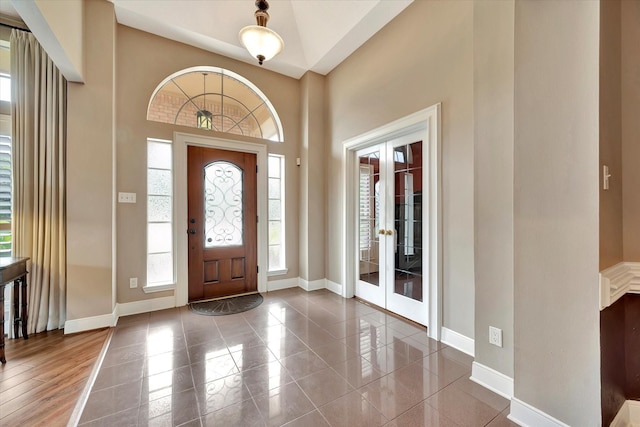 foyer featuring baseboards, french doors, and a high ceiling